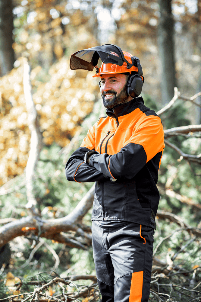 Arborist standing by some cut down trees