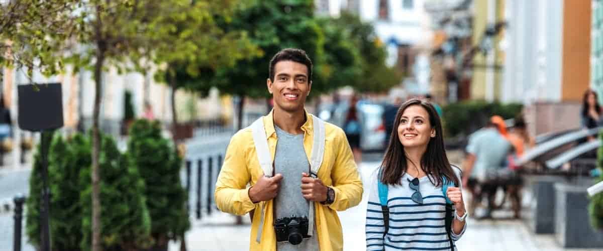 A couple walking in the city with trees in the background
