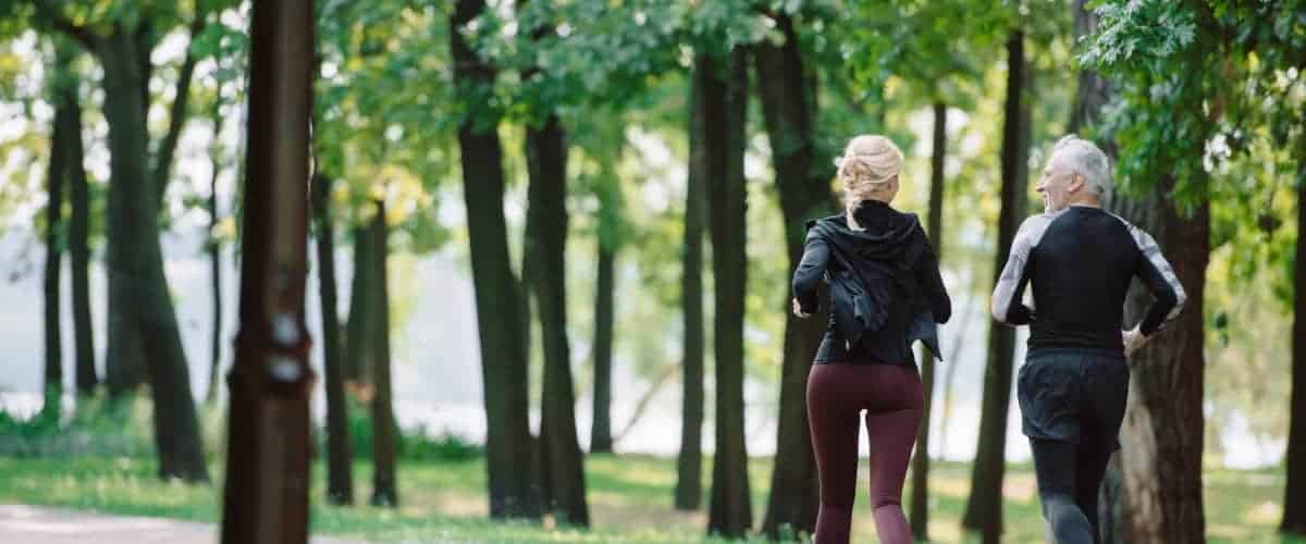 People jogging in a city park area surrounded by trees