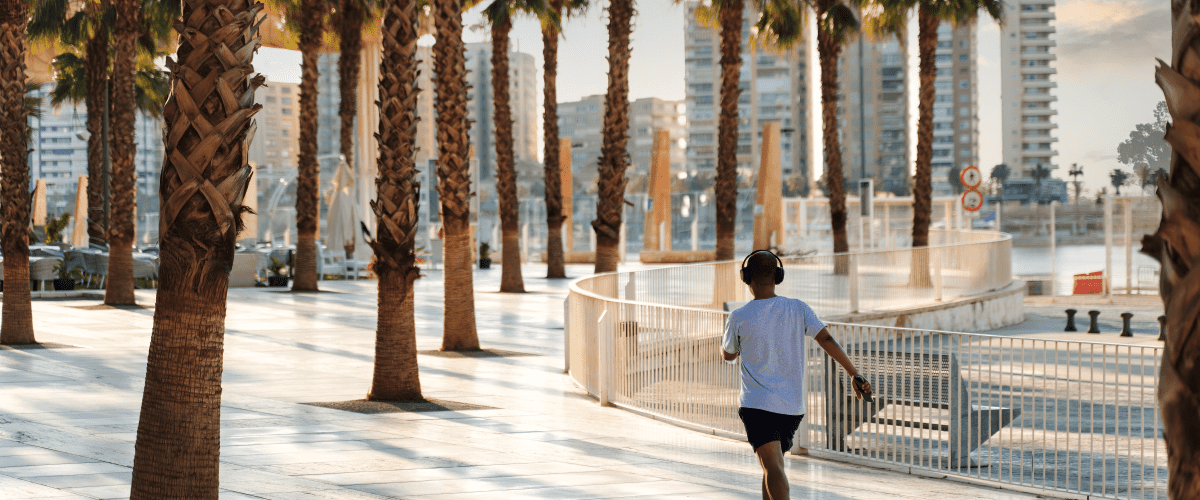Man speed walking through an urban area with large trees