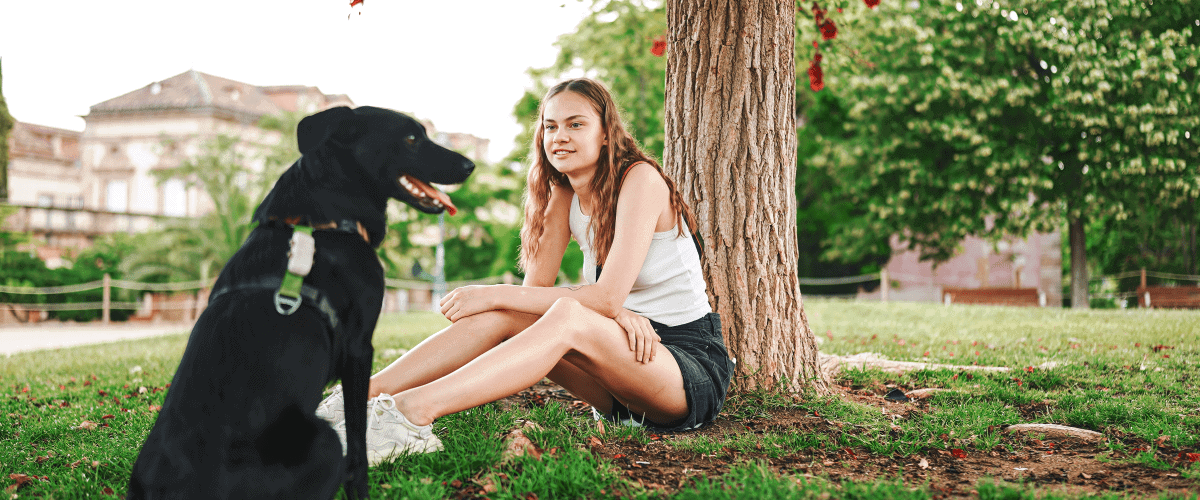 Young woman with her dog enjoying the air quality by a large tree